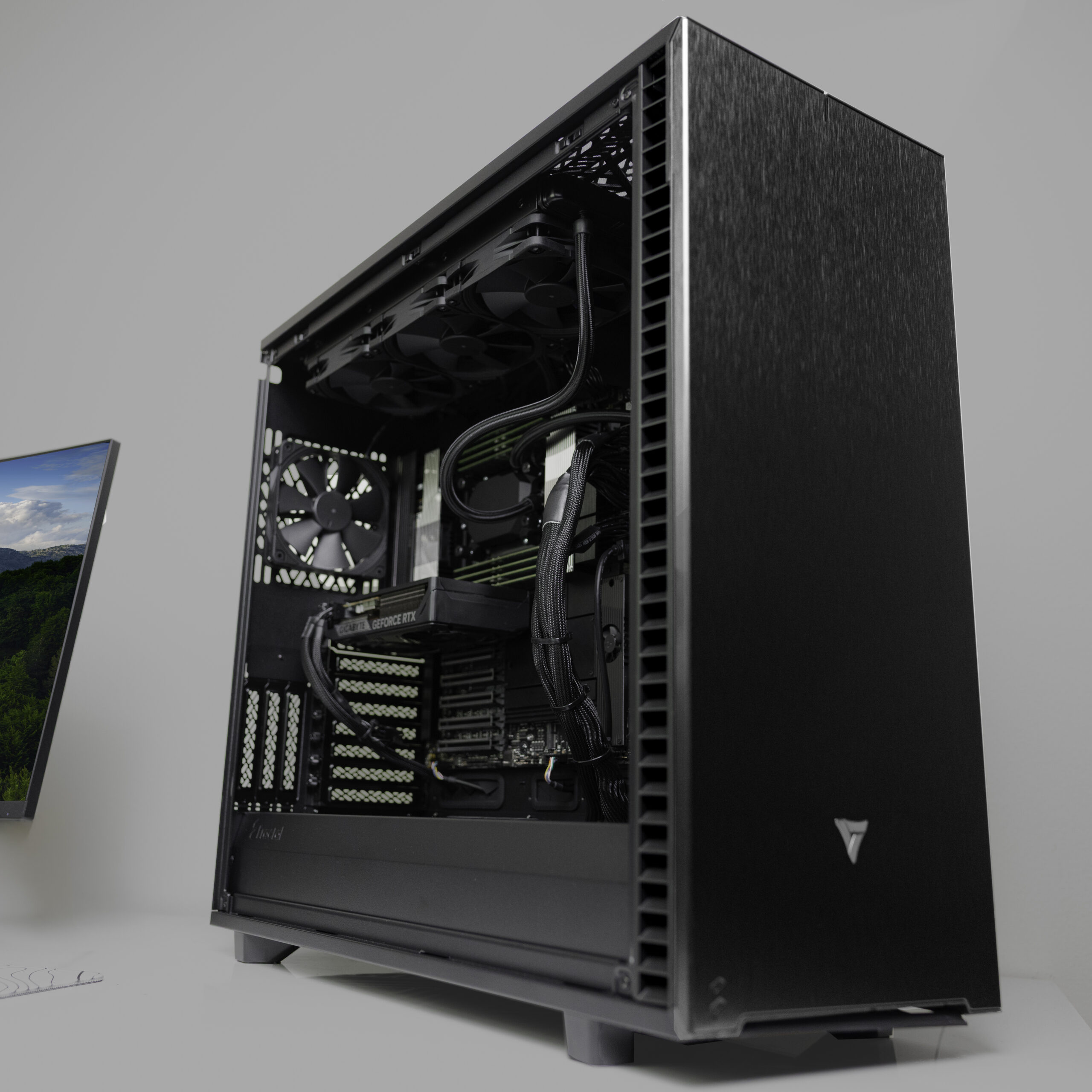 VRLA Tech open workstation setup featuring dual monitors, mechanical keyboard, and a custom hand-assembled black tower in a clean studio environment